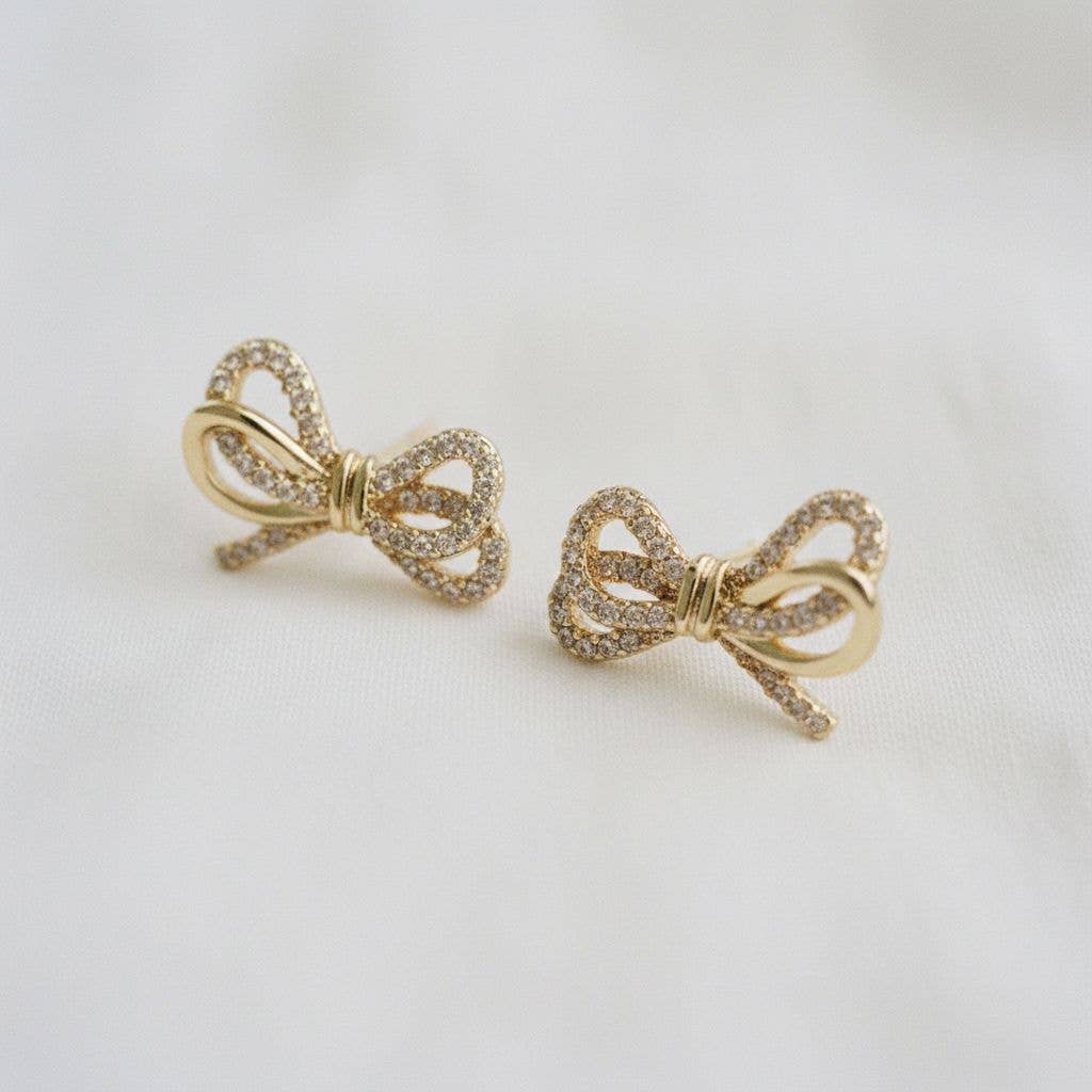 Gold bow-shaped earrings on a light gray background