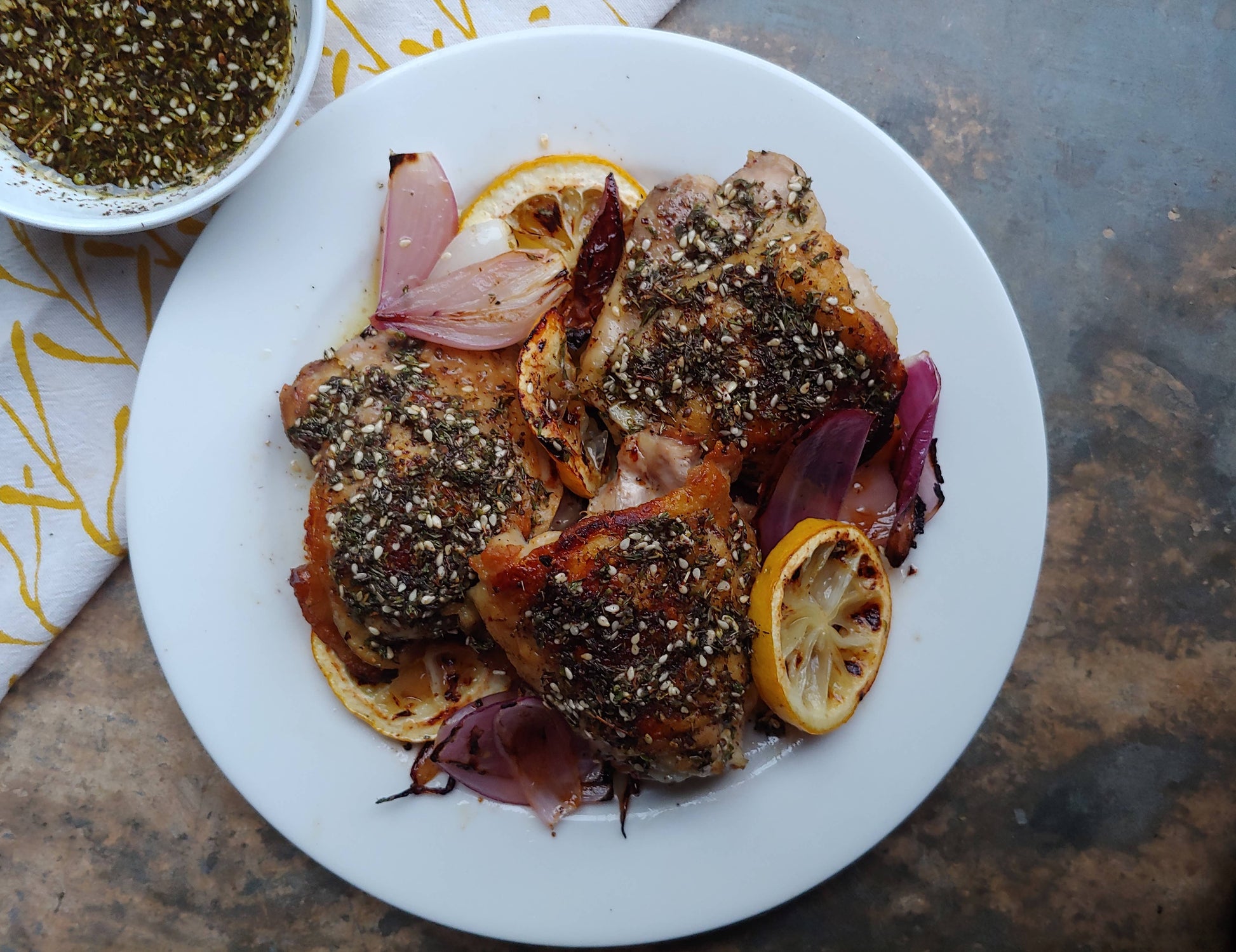 Plated dish of roasted chicken with lemon and onions on a rustic surface