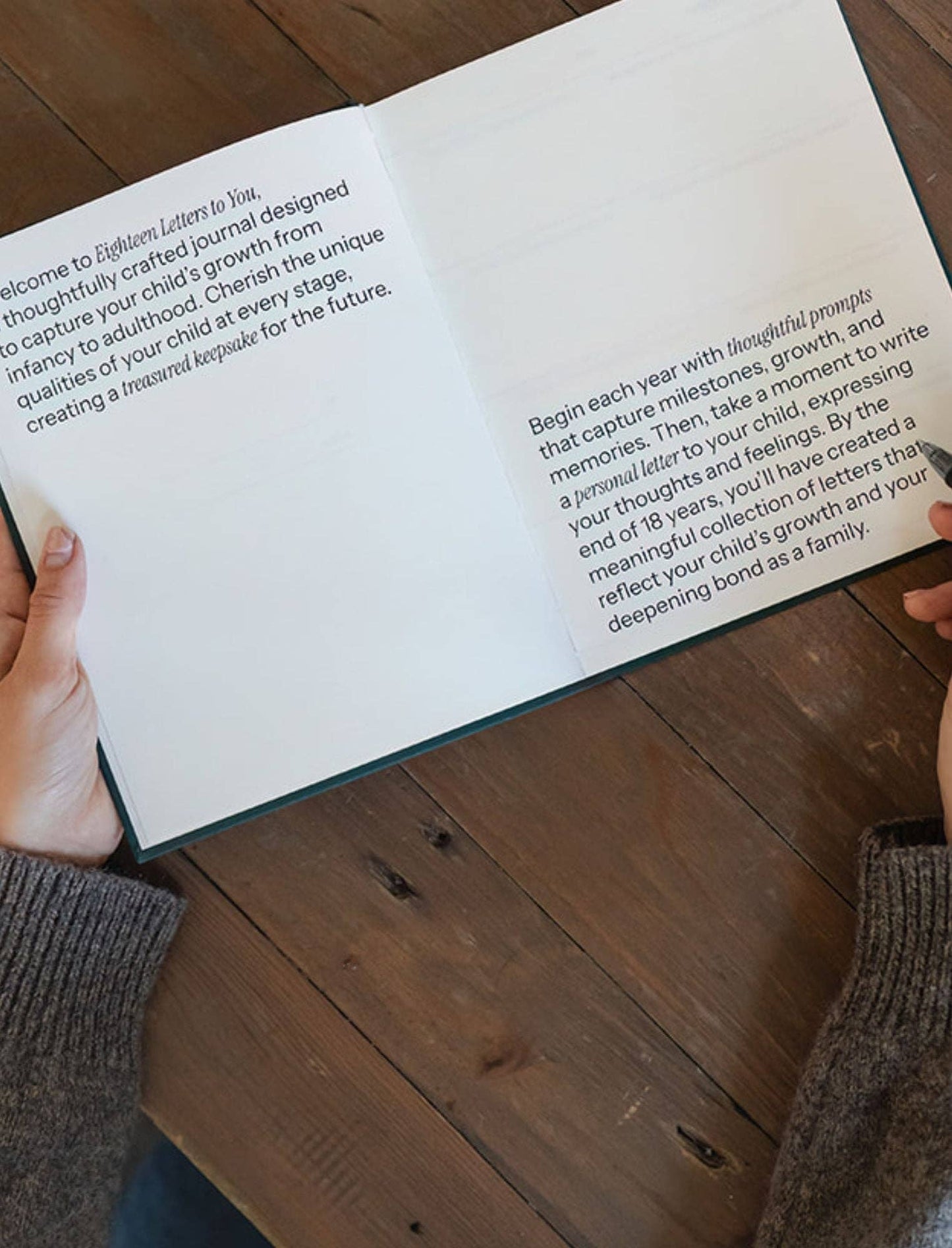 Person holding an open book with text on a wooden surface