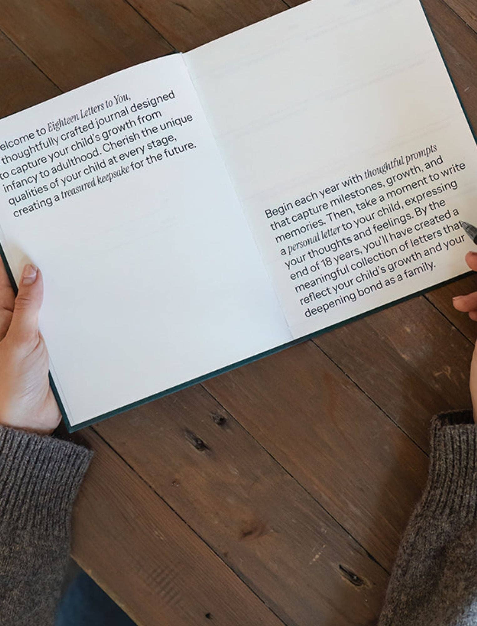 Person holding an open book with text on a wooden surface