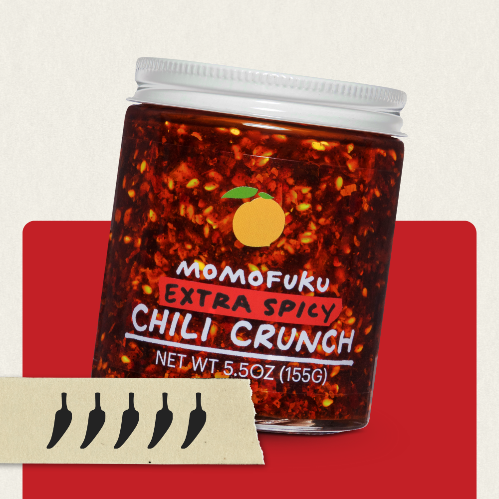 Jar of Momofuku Extra Spicy Chili Crunch on a red background