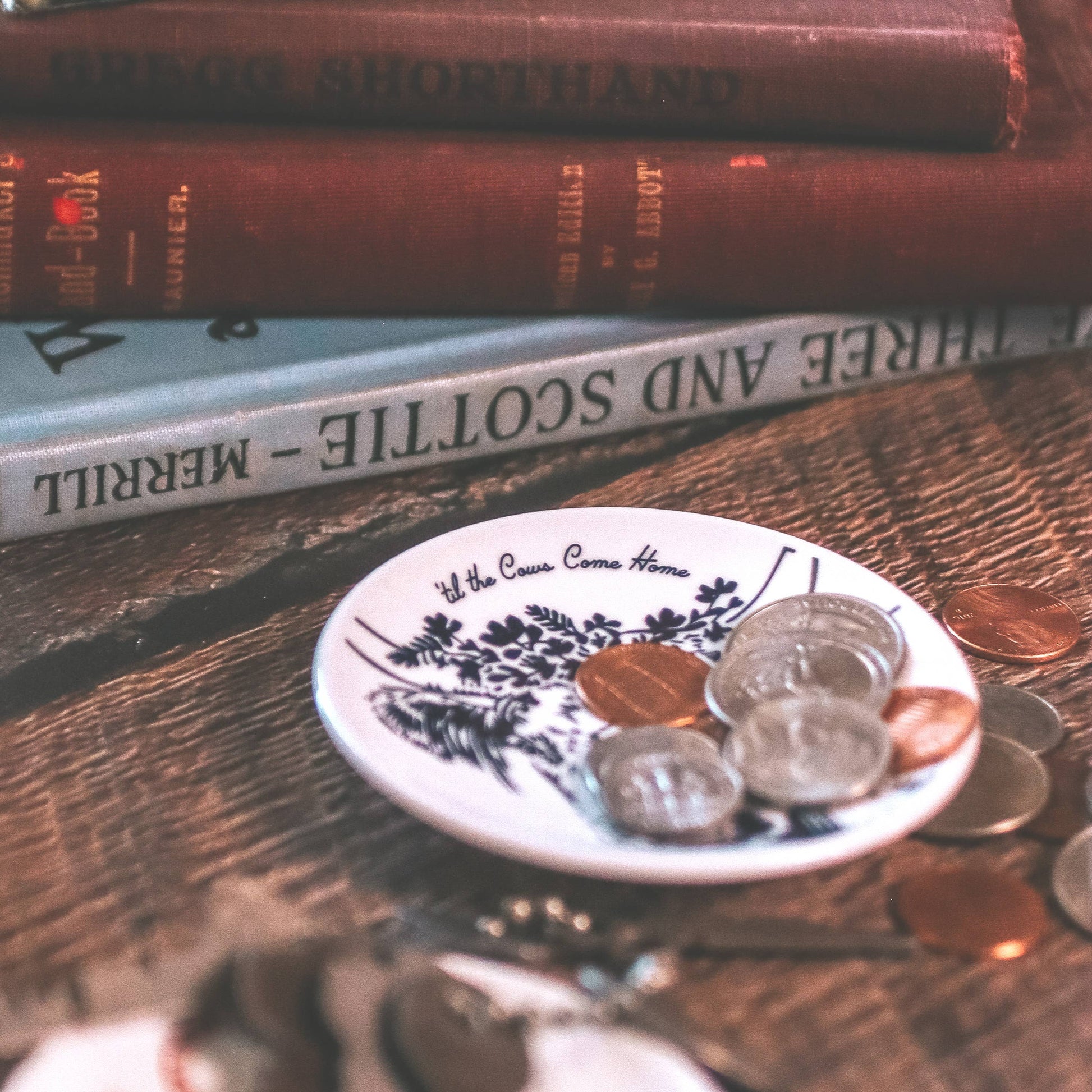 Stack of books with coins on a wooden surface