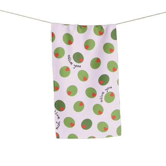 White tea towel with green olives with red heart pimentos pattern and text that reads "Olive You" on a white background