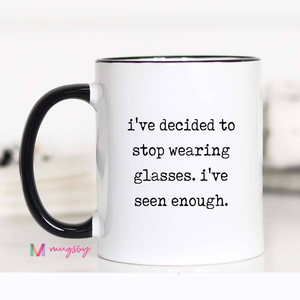 White mug with black handle and text 'i've decided to stop wearing glasses. i've seen enough.' on a white background