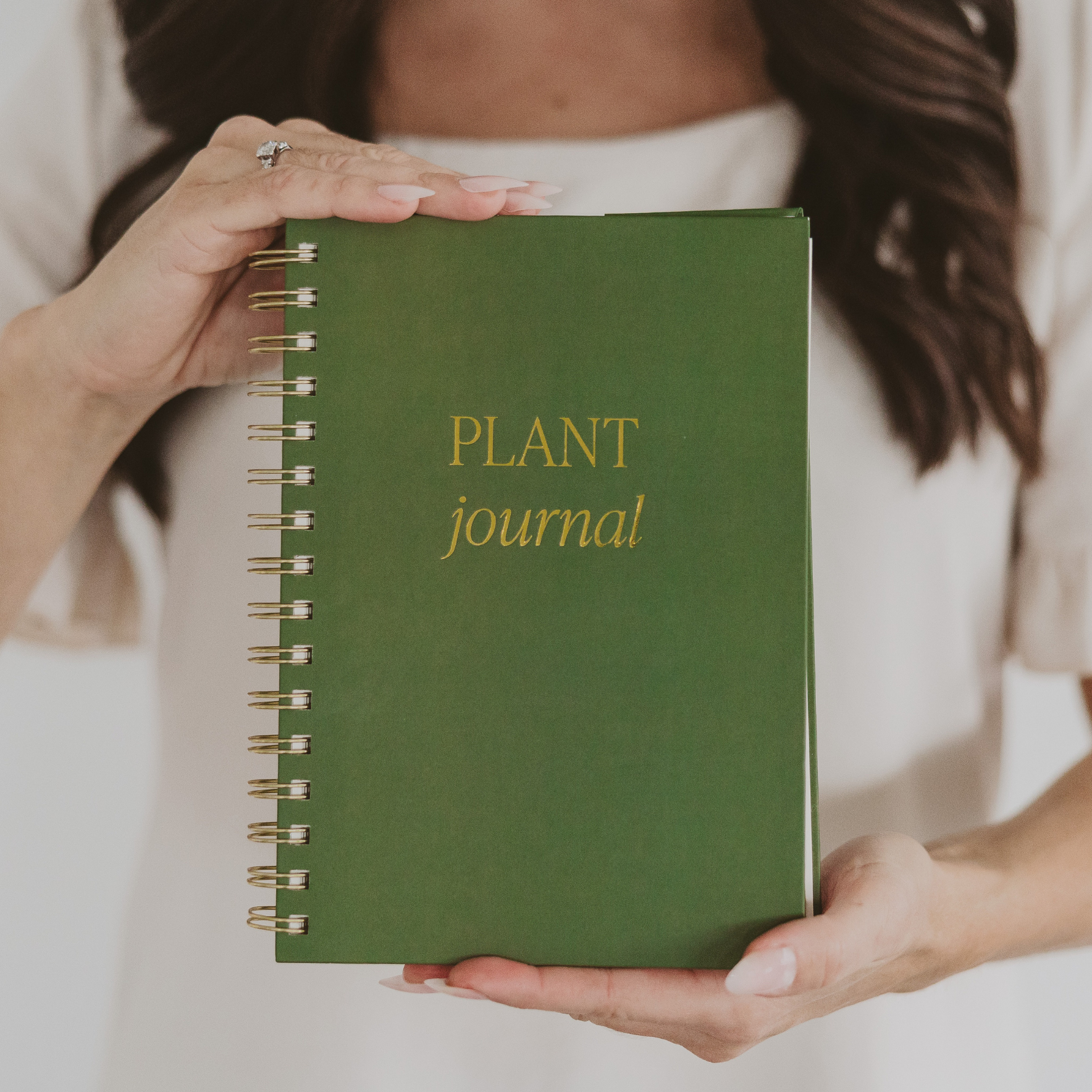Green notebook titled 'Plant journal' held by a person