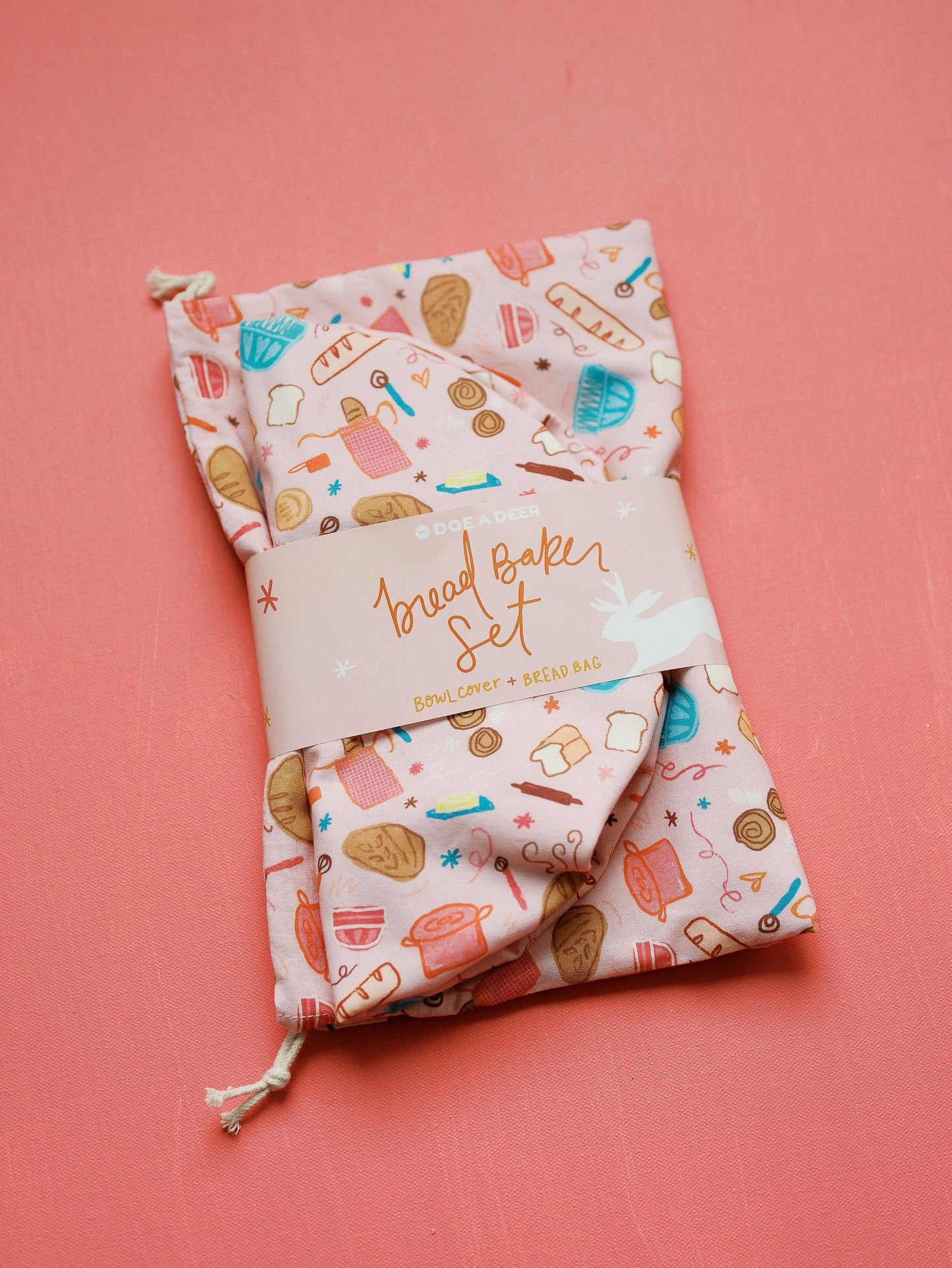 Folded fabric set with 'Bread Baker Set' packaging on a pink background