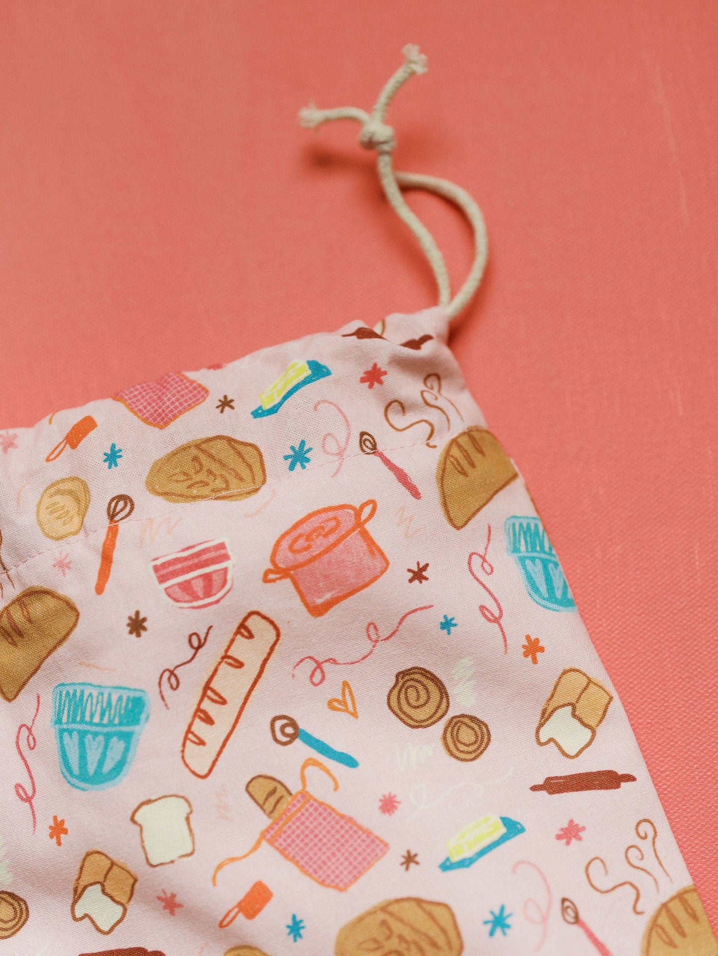 Drawstring bag with baking-themed illustrations on a pink background