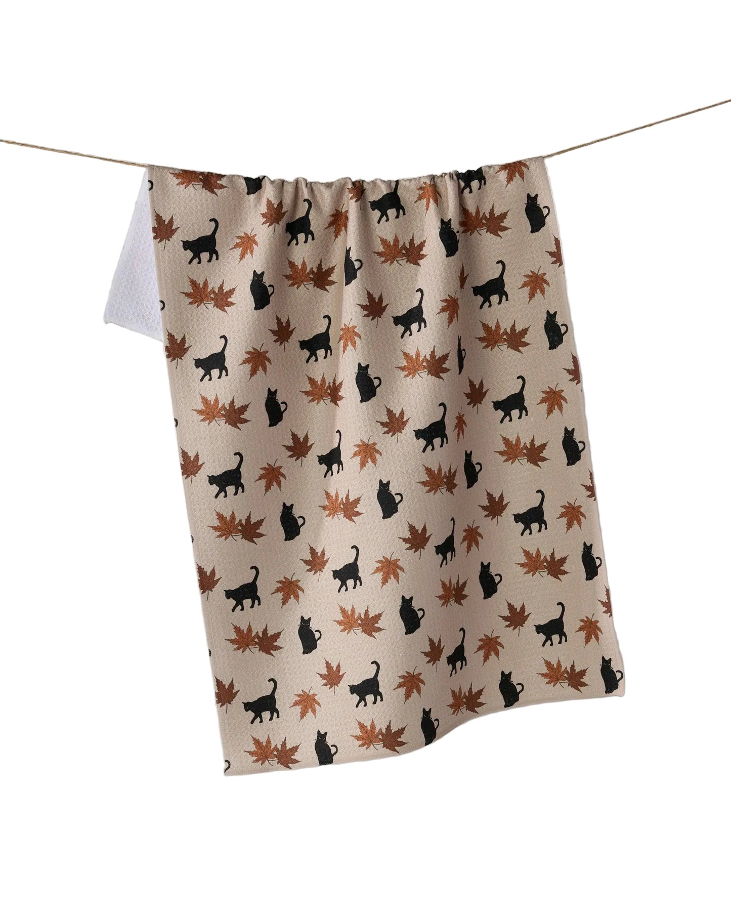 Fabric with black cat and brown leaf pattern hanging on a line against a white background