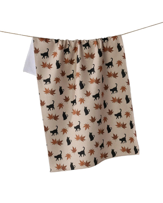 Fabric with black cat and brown leaf pattern hanging on a line against a white background