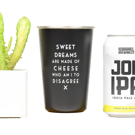 Black tumbler with humorous text next to a can of John IPPA beer on a white background