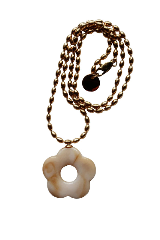 Gold chain necklace with a floral pendant on a light gray background