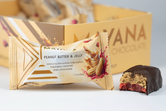 Peanut Butter & Jelly chocolate bar with packaging and a piece of the bar on a white surface.