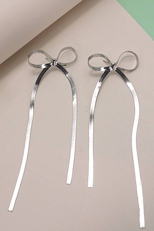 Two silver snakechain bow earrings on an off white background