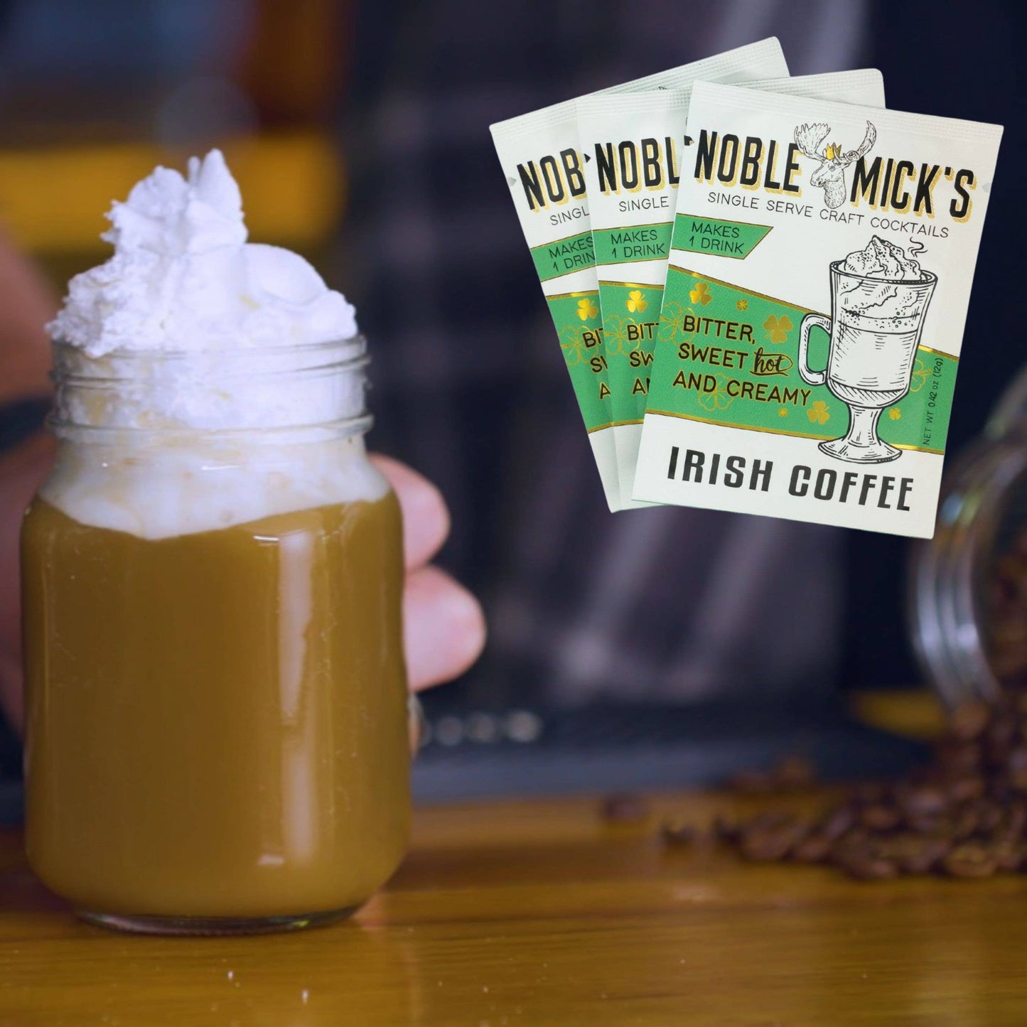 Irish coffee in a jar with whipped cream and Noble Mick's Irish Coffee packets in the background.