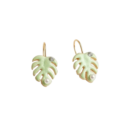 Pair of green monstera leaf-shaped earrings with a pearl and rhinestone detail on a white background