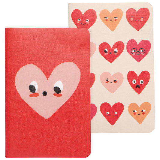 Two notebooks with heart-shaped covers featuring facial expressions on a white background