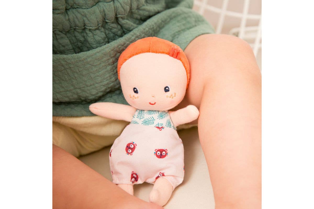 Small plush toy with a red hat held by a person's hand