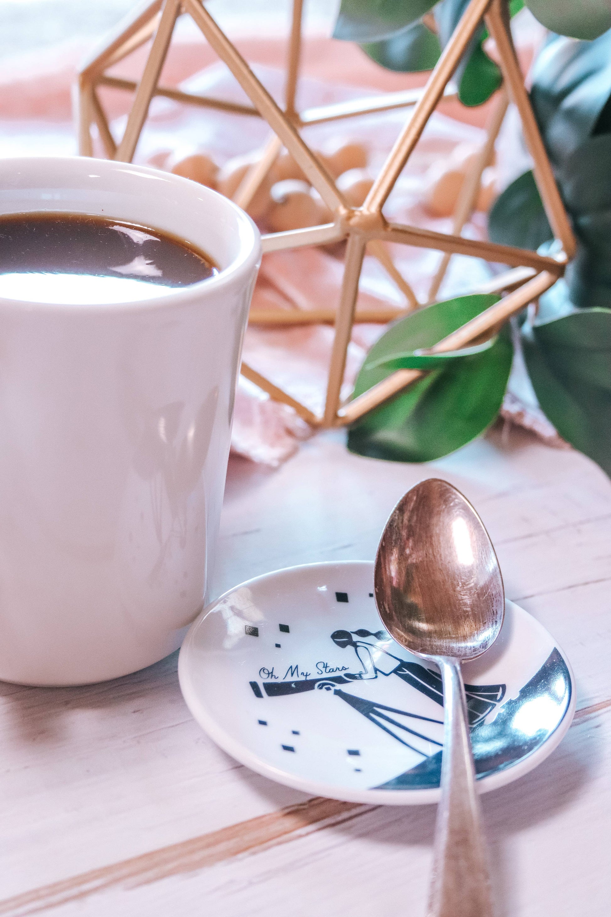 White mug with coffee, spoon, and decorative elements on a light surface