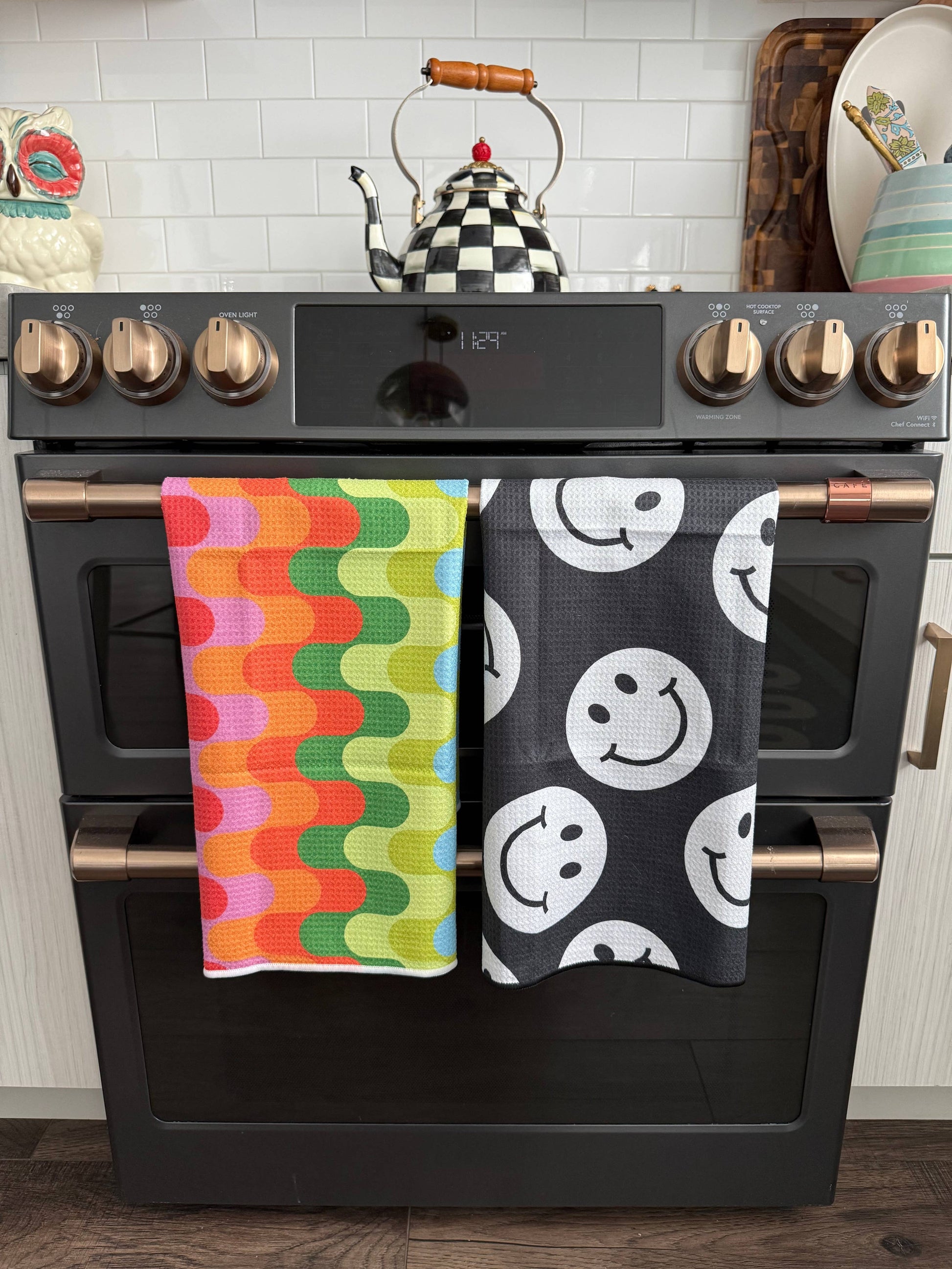 Black oven with colorful and patterned towels hanging on the handle