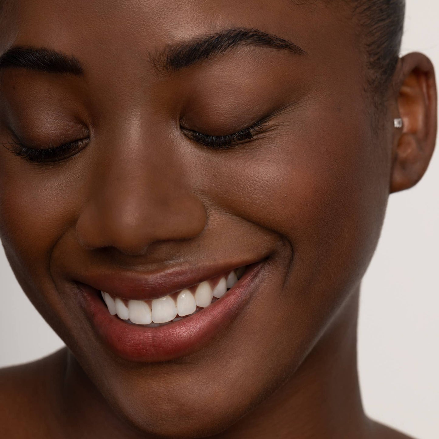Close-up of a woman's face with a soft smile on a neutral background