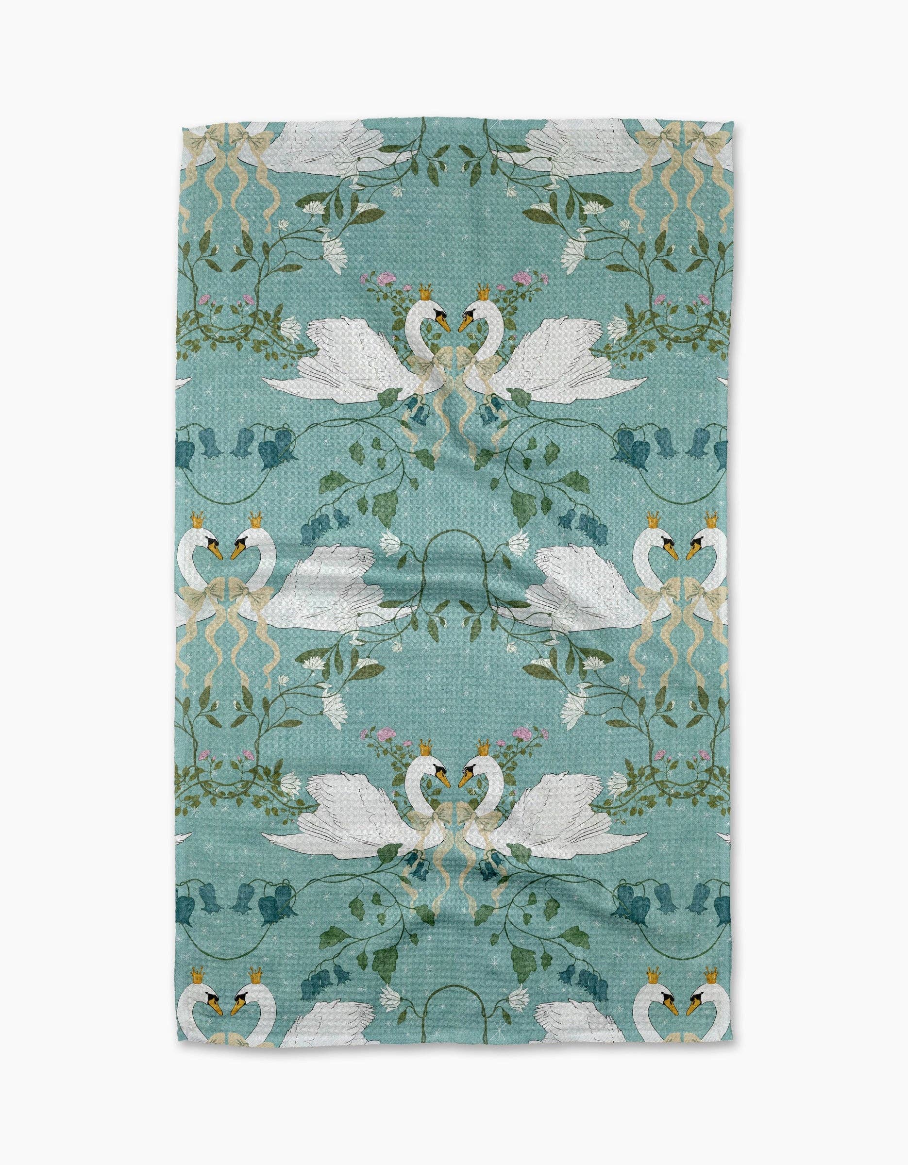 Teal tea towel with a pattern depicting two swans facing each other, surrounded by leaves and flowers, on a white background