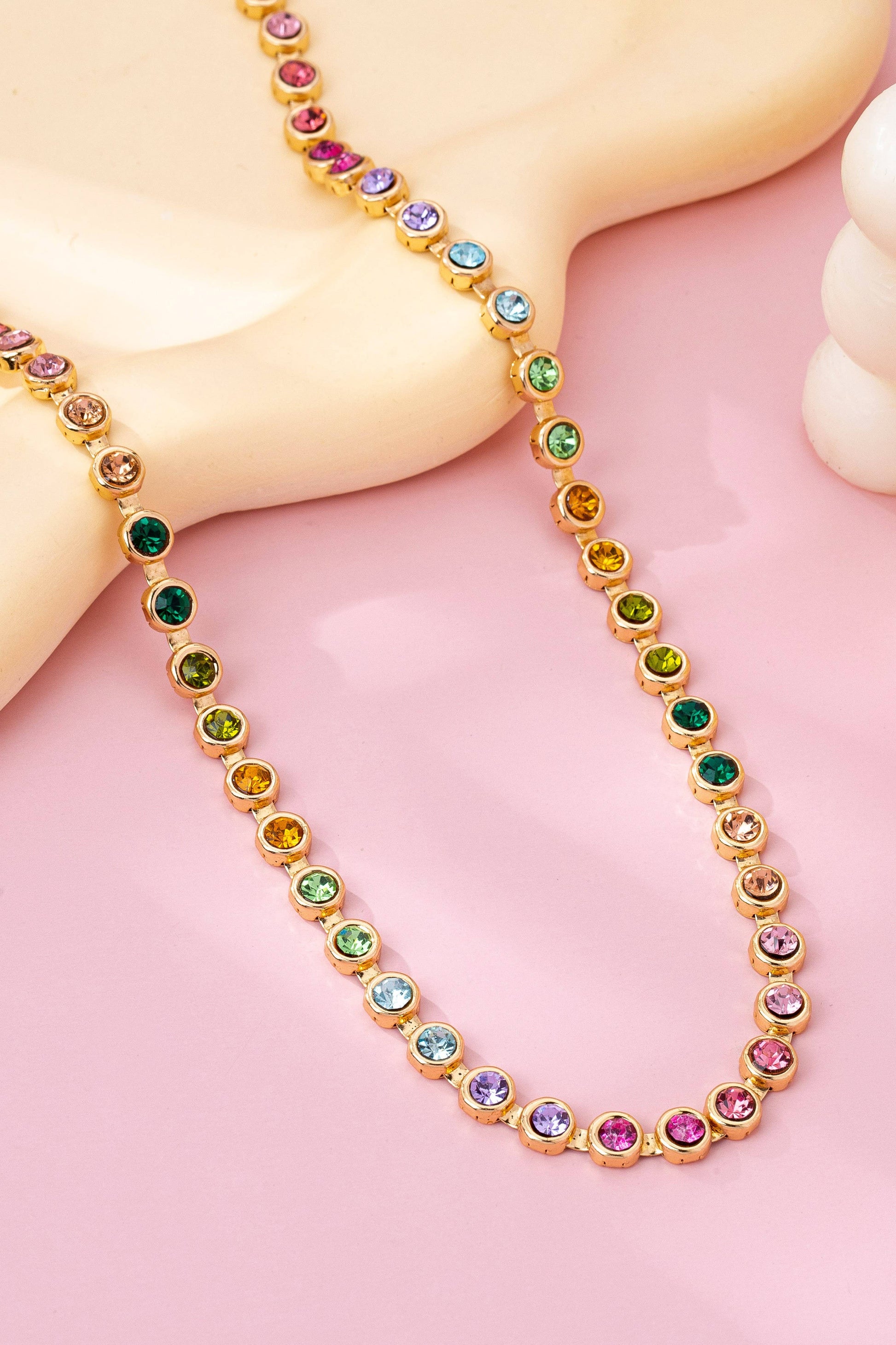 Necklace with multicolored gemstones on a pink background