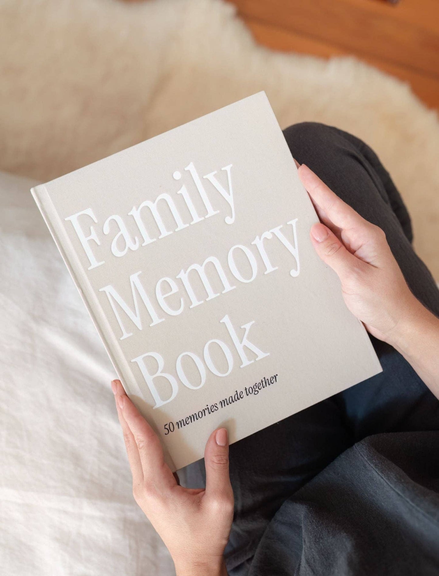 Person holding a 'Family Memory Book' on a soft surface