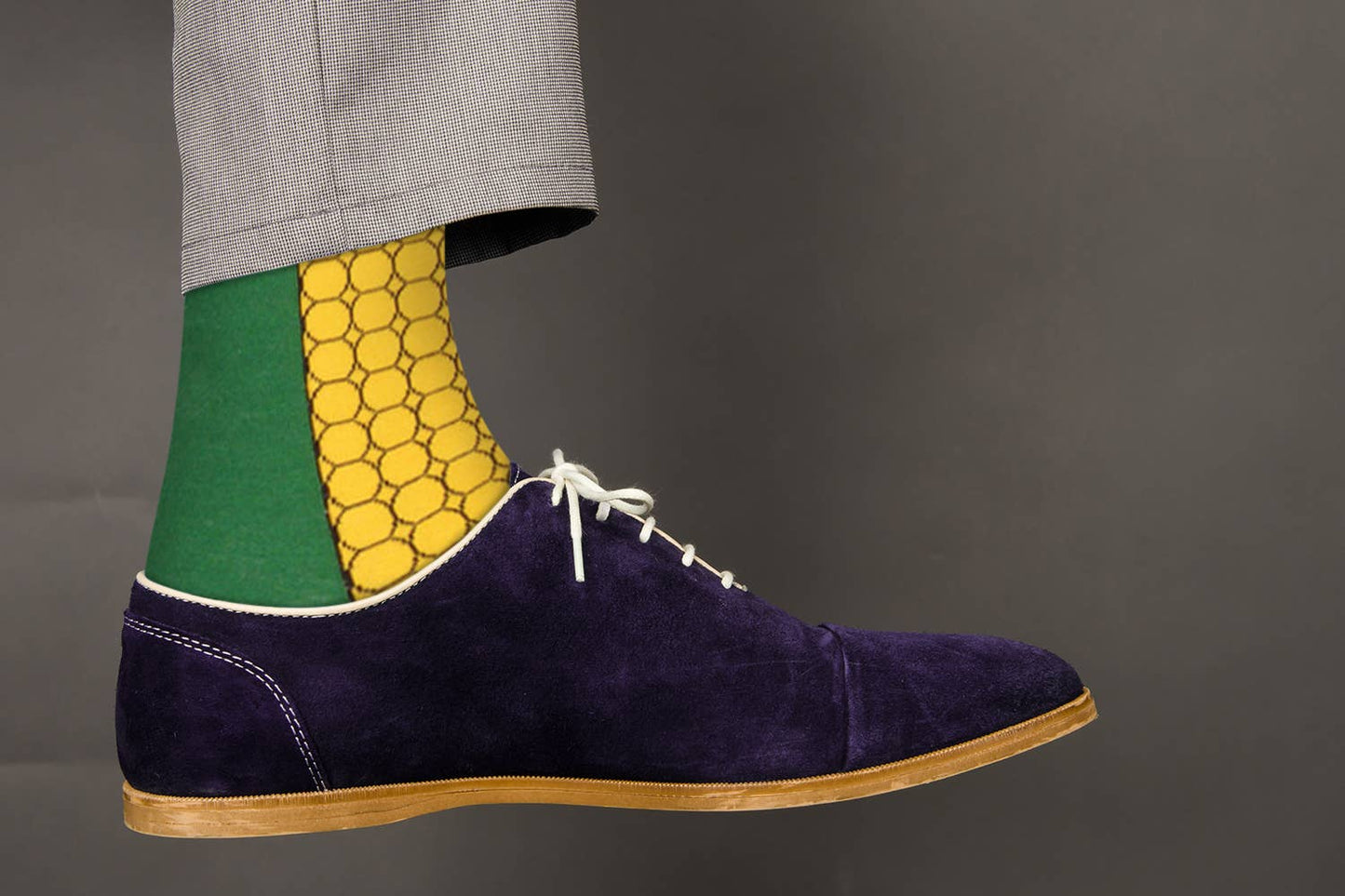 Navy suede shoe with a colorful sock on a gray background