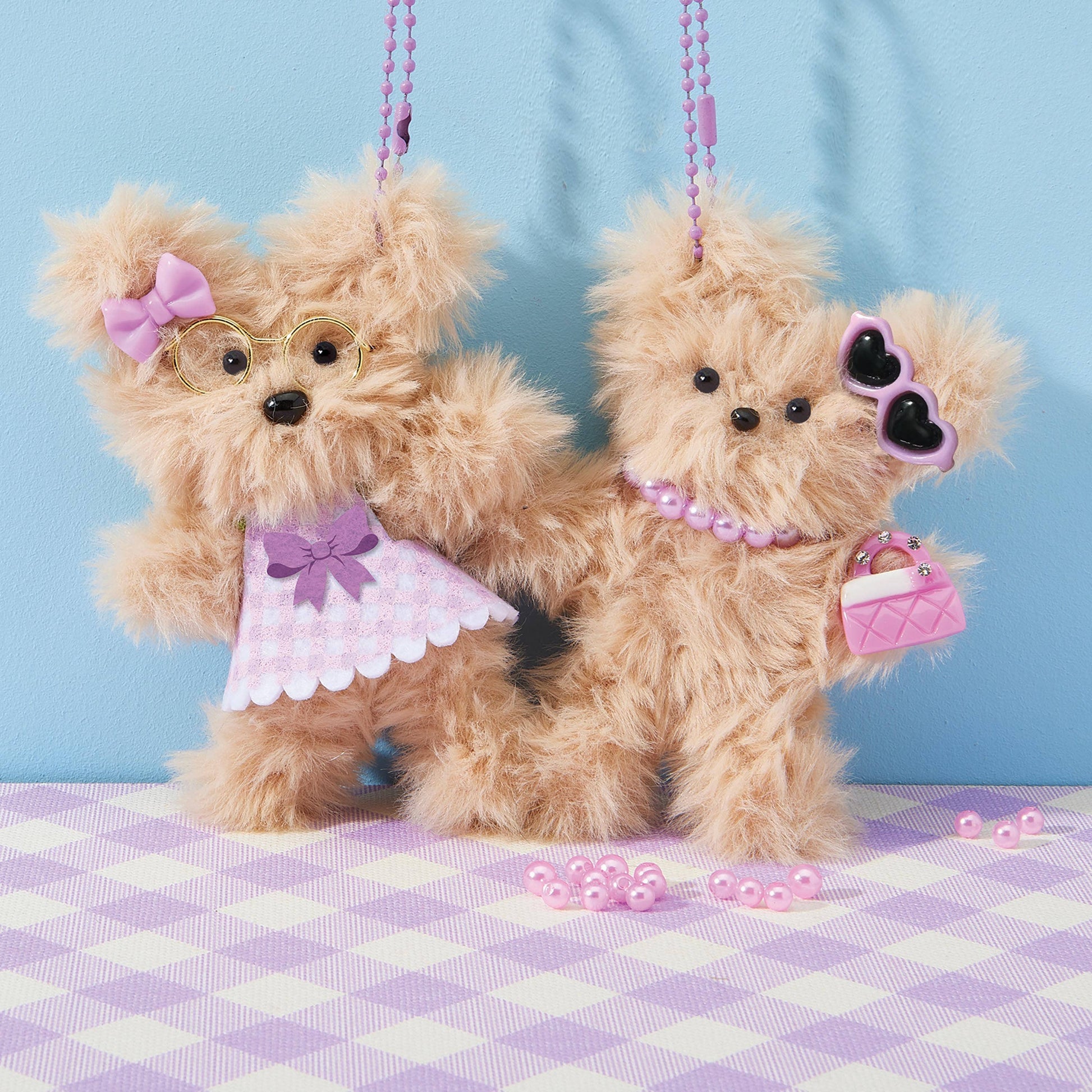 Two plush toy dogs with accessories on a checkered surface against a blue background