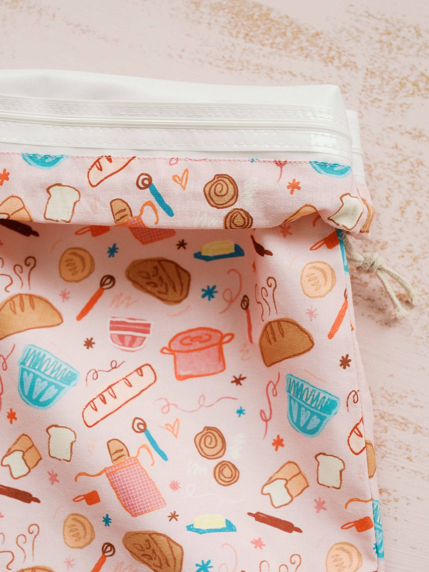 Reusable food wrap with bread and kitchen utensil pattern on a light background
