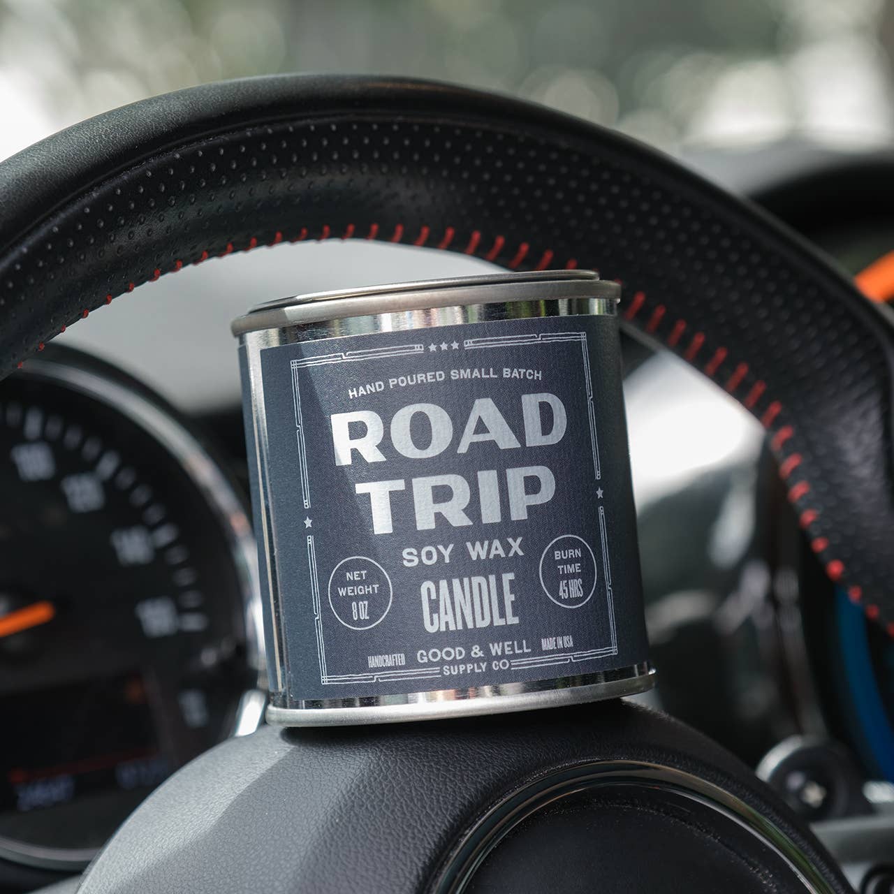 Candle labeled 'Road Trip' on a car dashboard
