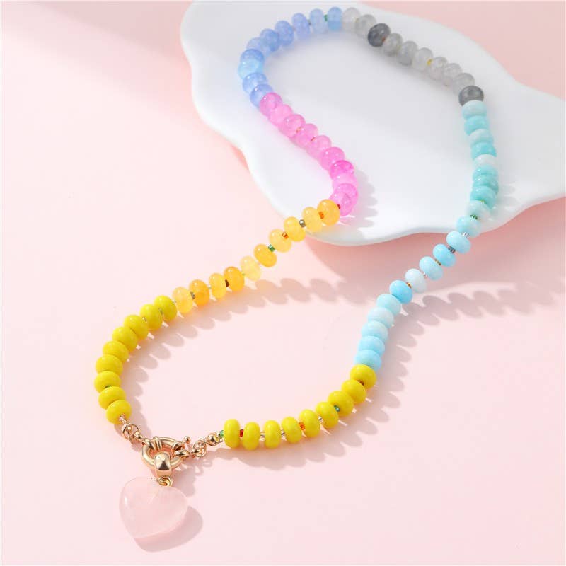 Colorful beaded necklace with a yellow accent on a pink surface
