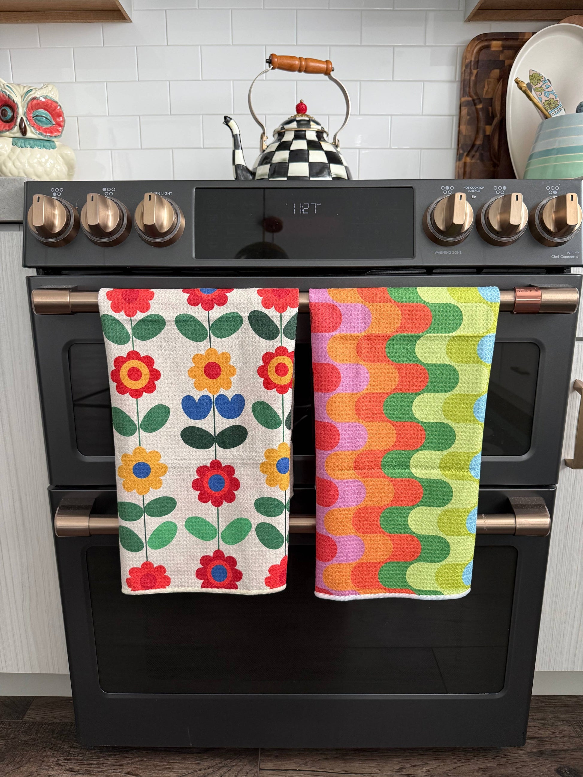 Colorful kitchen towels hanging on a black stove in a kitchen setting.
