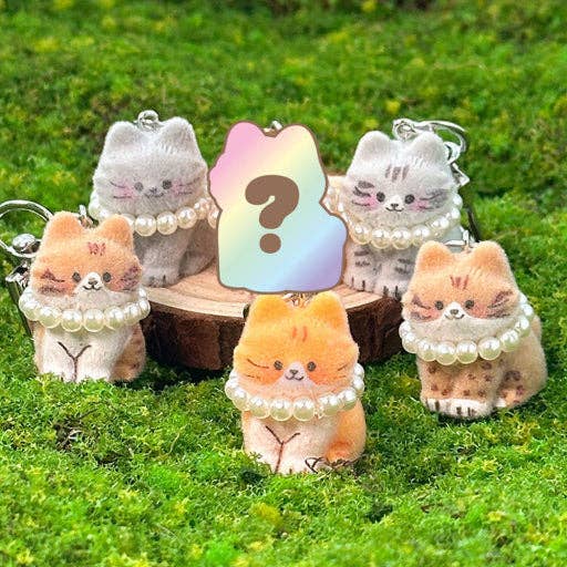 Set of cute animal plush keychains with pearl necklaces on a grassy background
