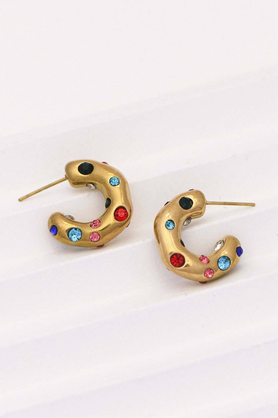 Gold hoop earrings with colorful gemstones on a white background