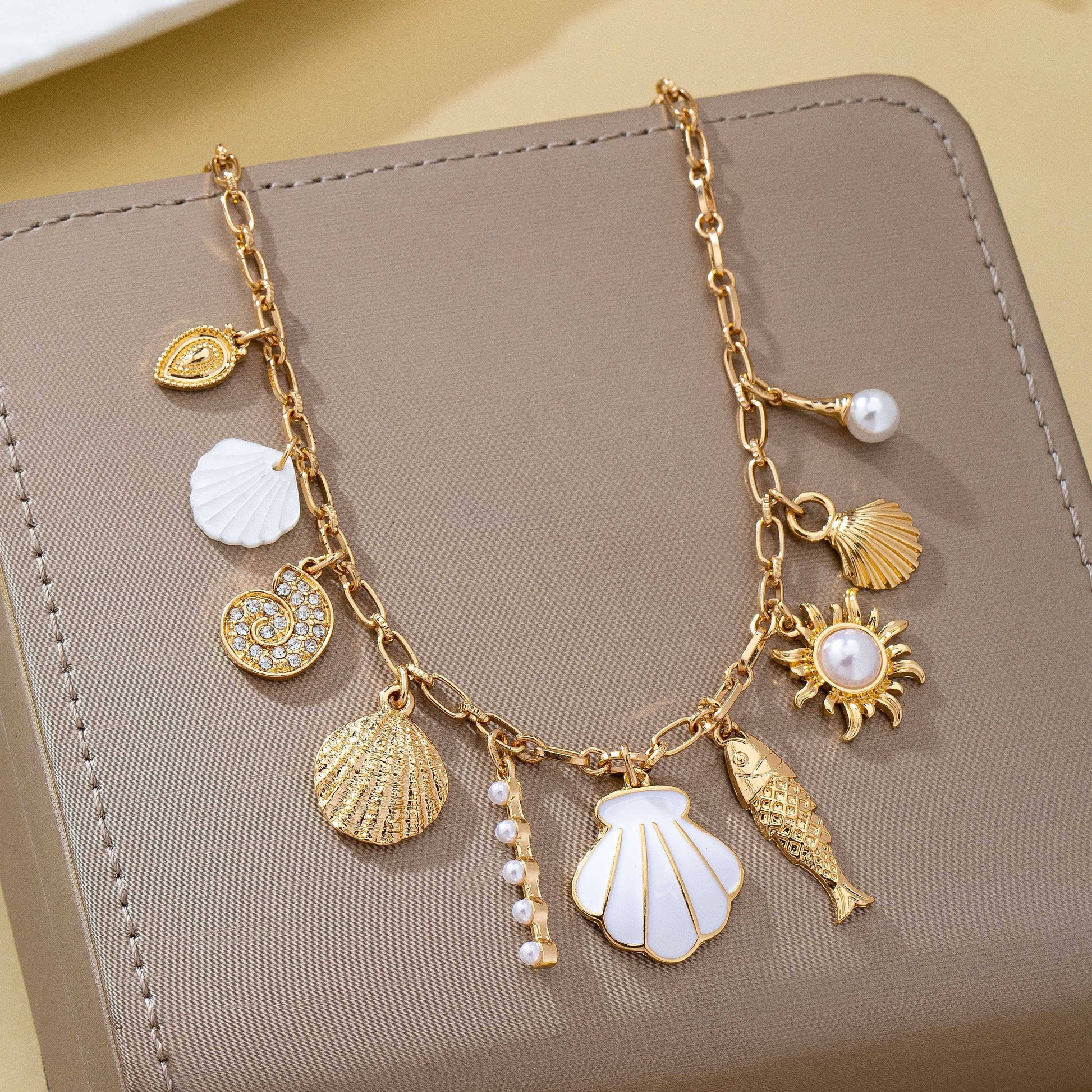 Gold necklace with various charms on a beige surface