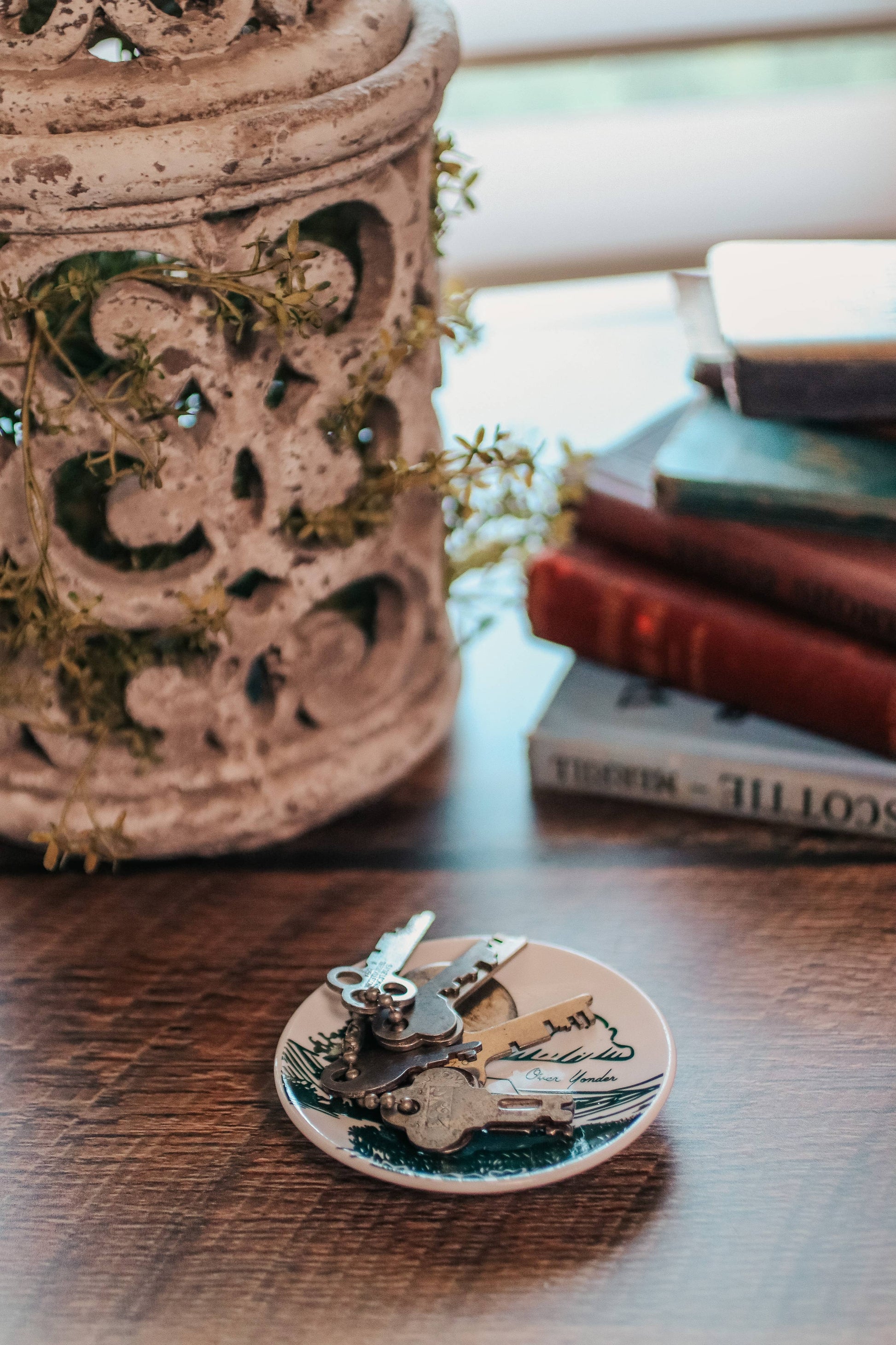 Decorative items including a ceramic pot, books, and a small plate with keys on a wooden surface.