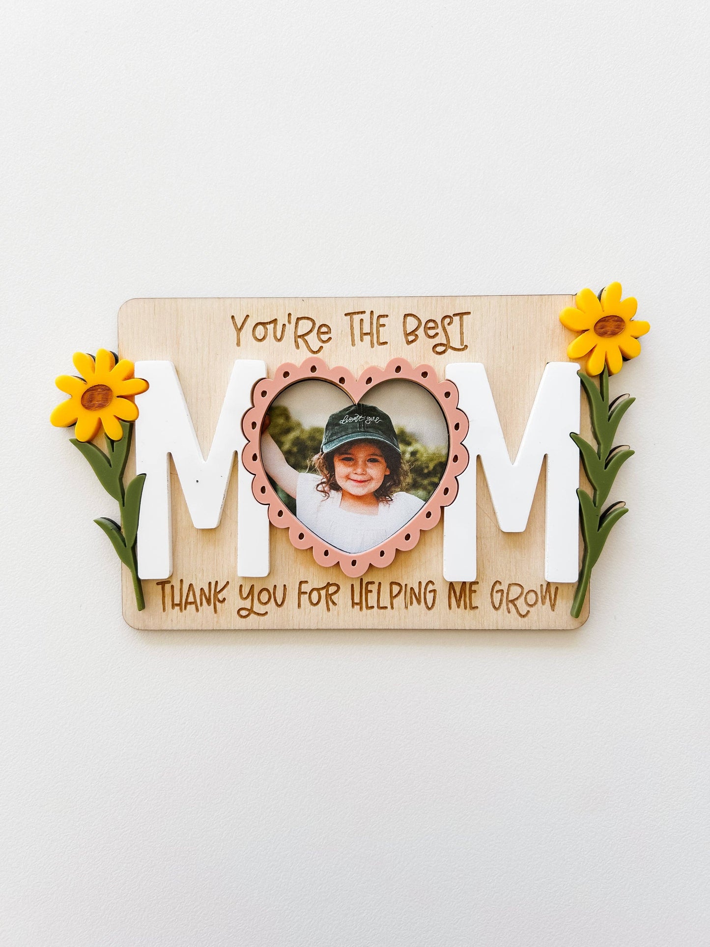 Decorative wall art with 'MOM' and a photo of a child, on a white background