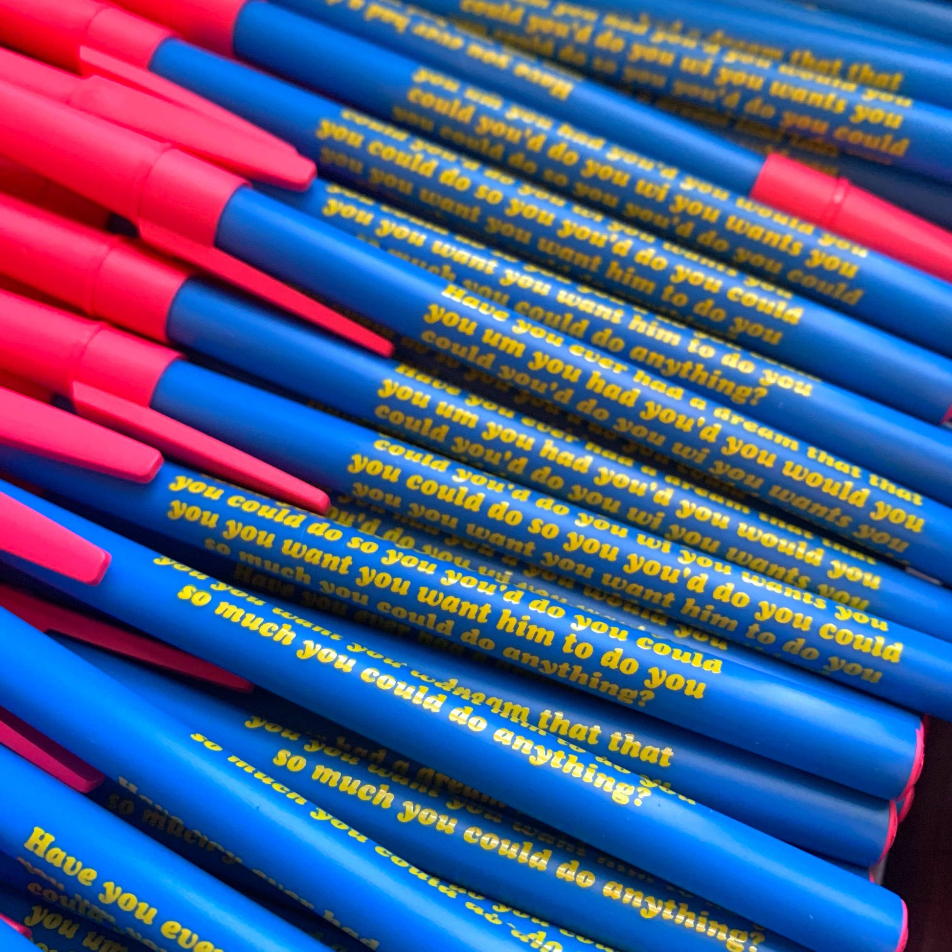 Stack of blue and pink pens with text on the barrel