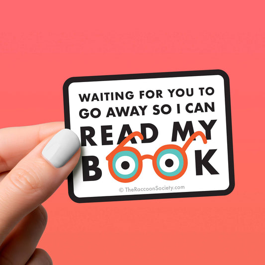 Hand holding a sticker with text and glasses illustration on a pink background