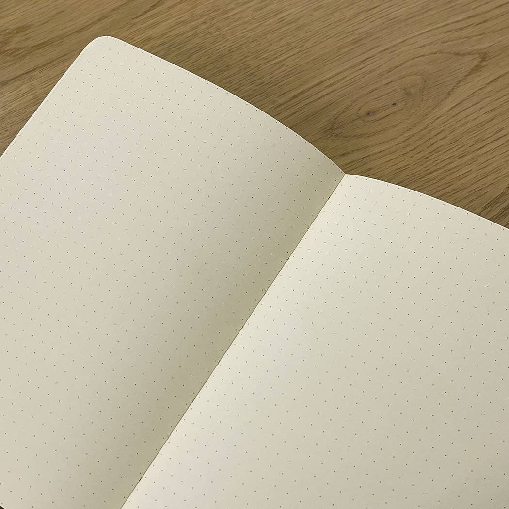 Open notebook with dot grid on cream pages on a wooden surface