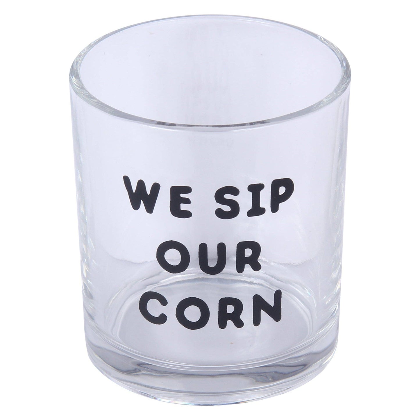 A clear glass tumbler with the humorous phrase 'WE SIP OUR CORN' printed in black capital letters on the front, set against a plain white background.