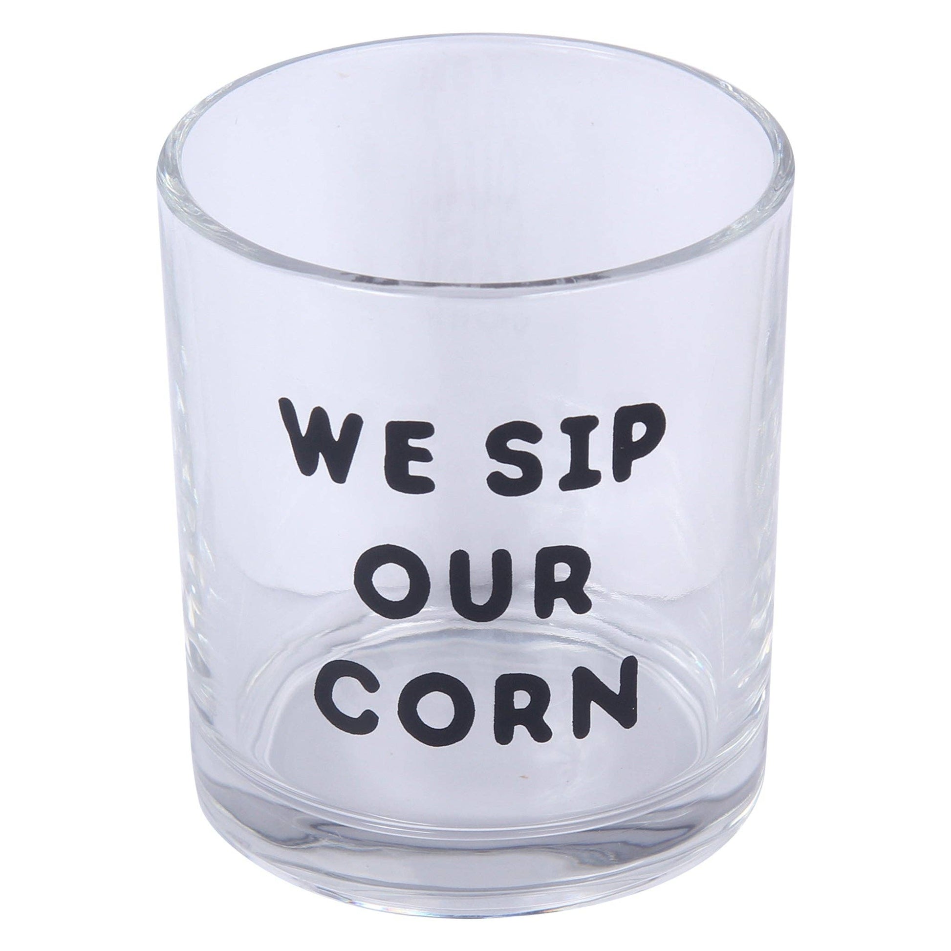 A clear glass tumbler with the humorous phrase 'WE SIP OUR CORN' printed in black capital letters on the front, set against a plain white background.