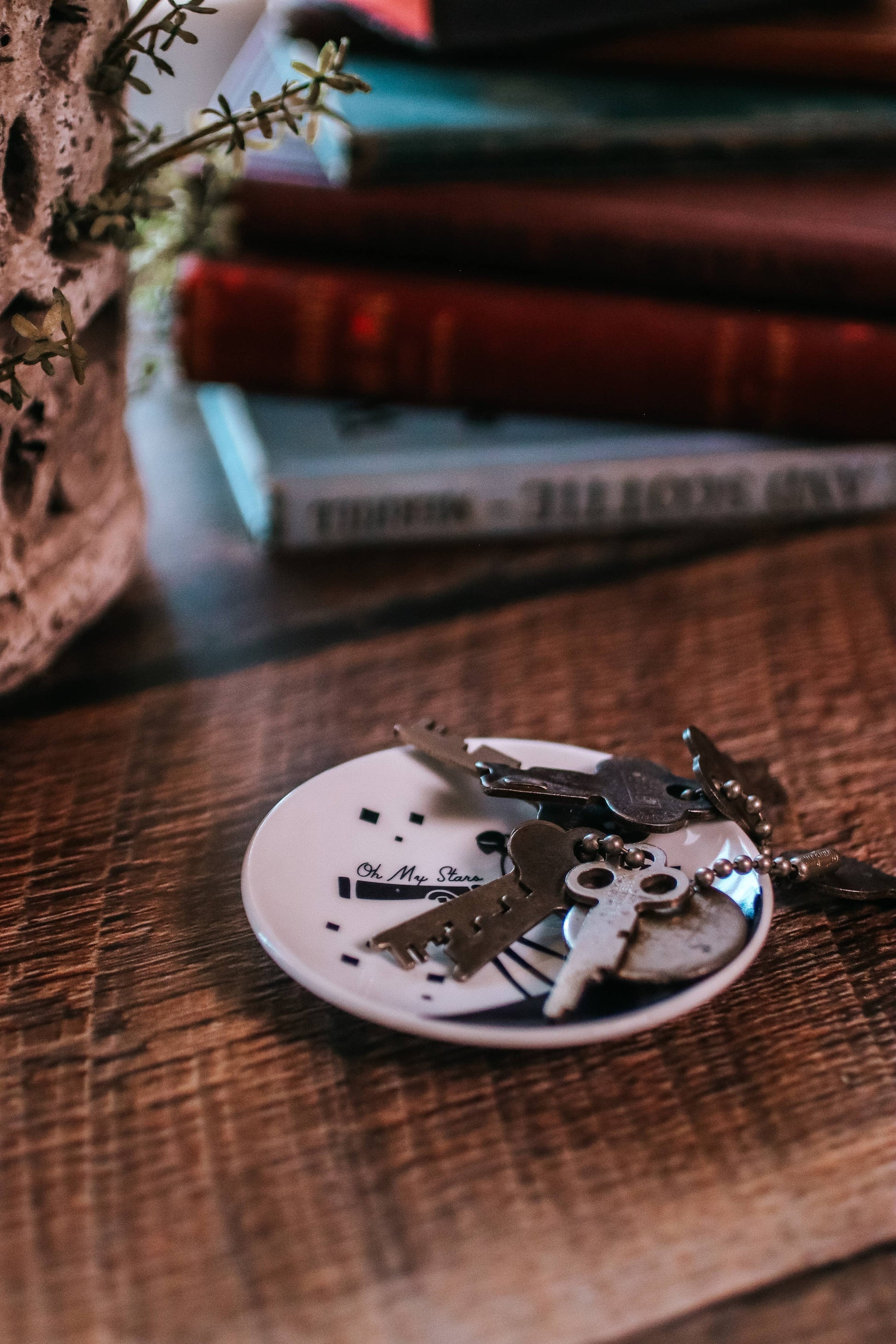 Decorative keychain on a small round plate with books in the background