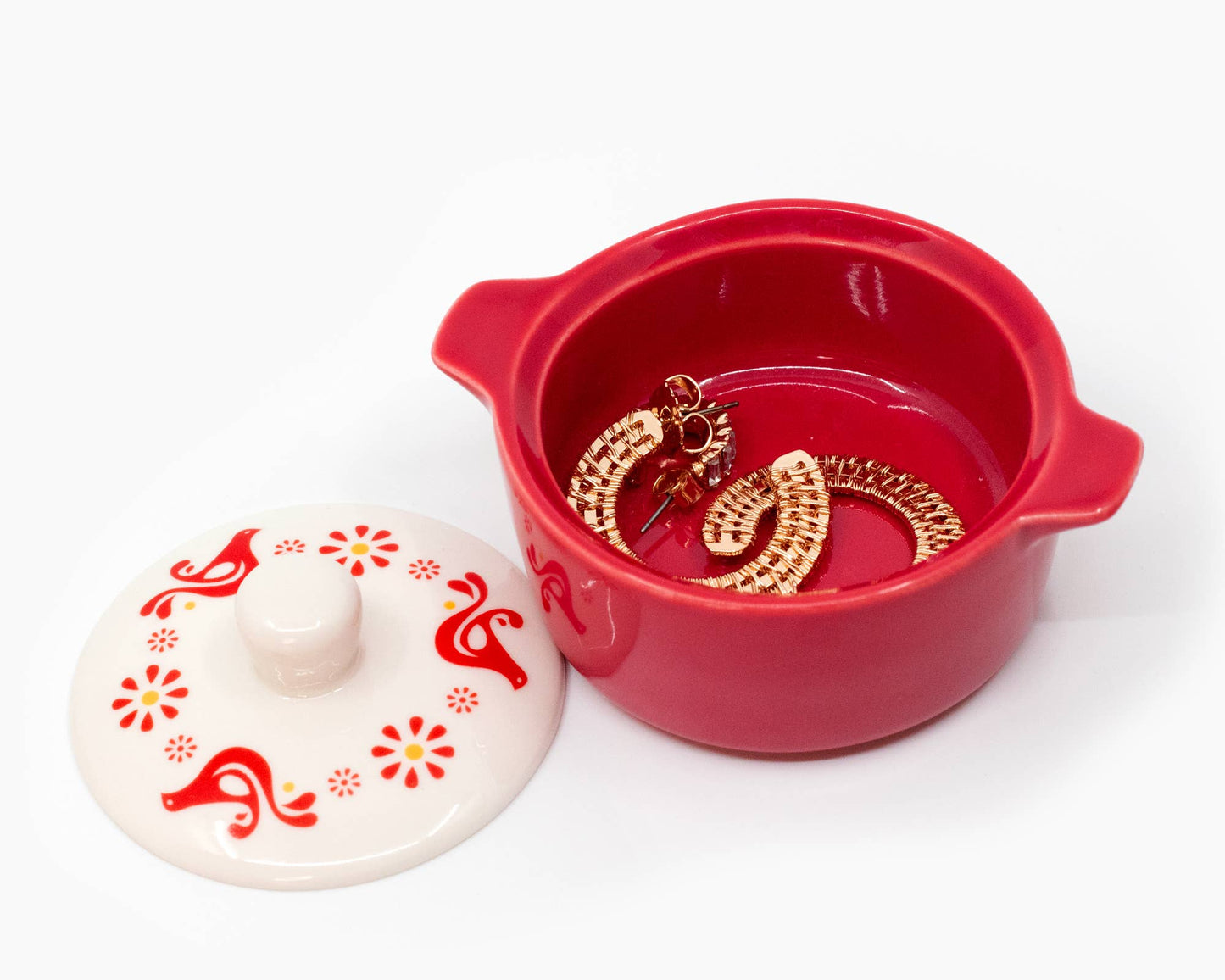 Red jewelry box with gold earrings and a white lid with red floral patterns on a white background