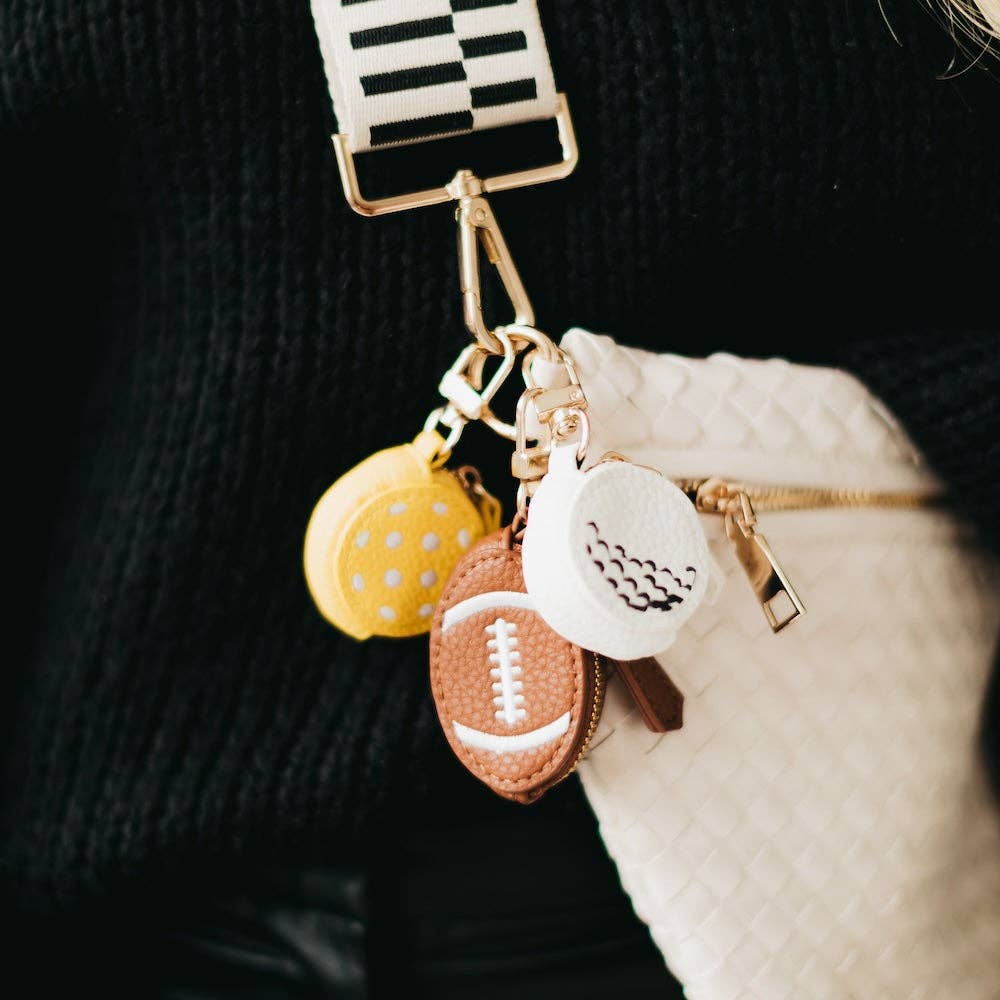 Keychain with various charms including a football, pickleball, and golfball on a dark background