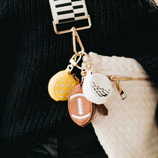 Keychain with various charms including a football, pickleball, and golfball on a dark background