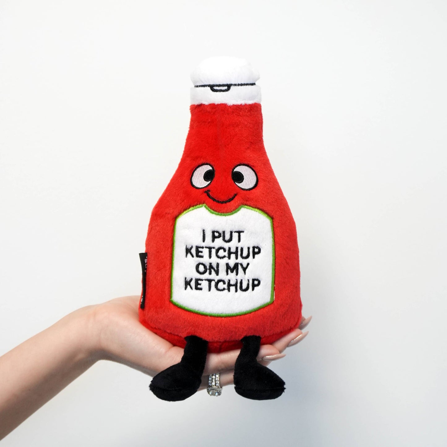 Plush toy resembling a ketchup bottle with text on a white background
