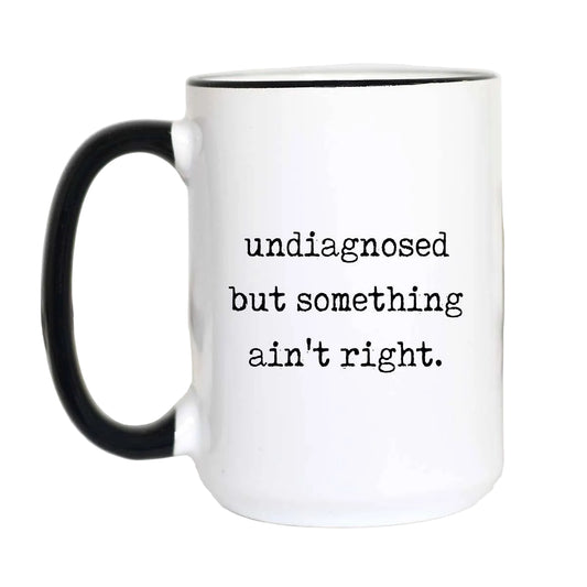 White mug with black handle and text 'undiagnosed but something ain't right.' on a white background