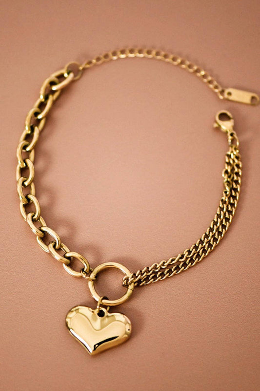 Gold chain bracelet with a heart-shaped charm on a brown background